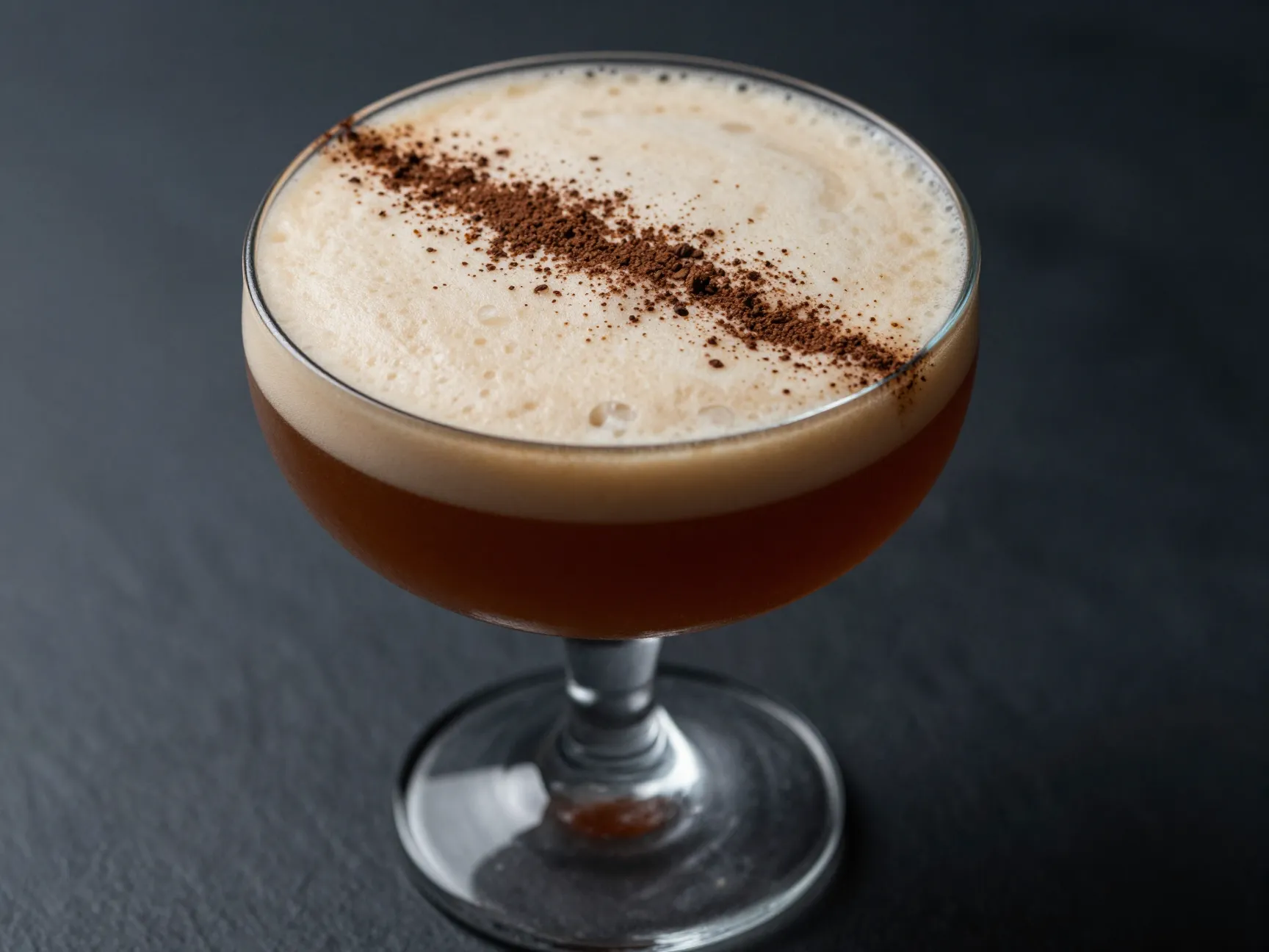 Cinematic dark amber espresso mocktail in coupe glass cream foam