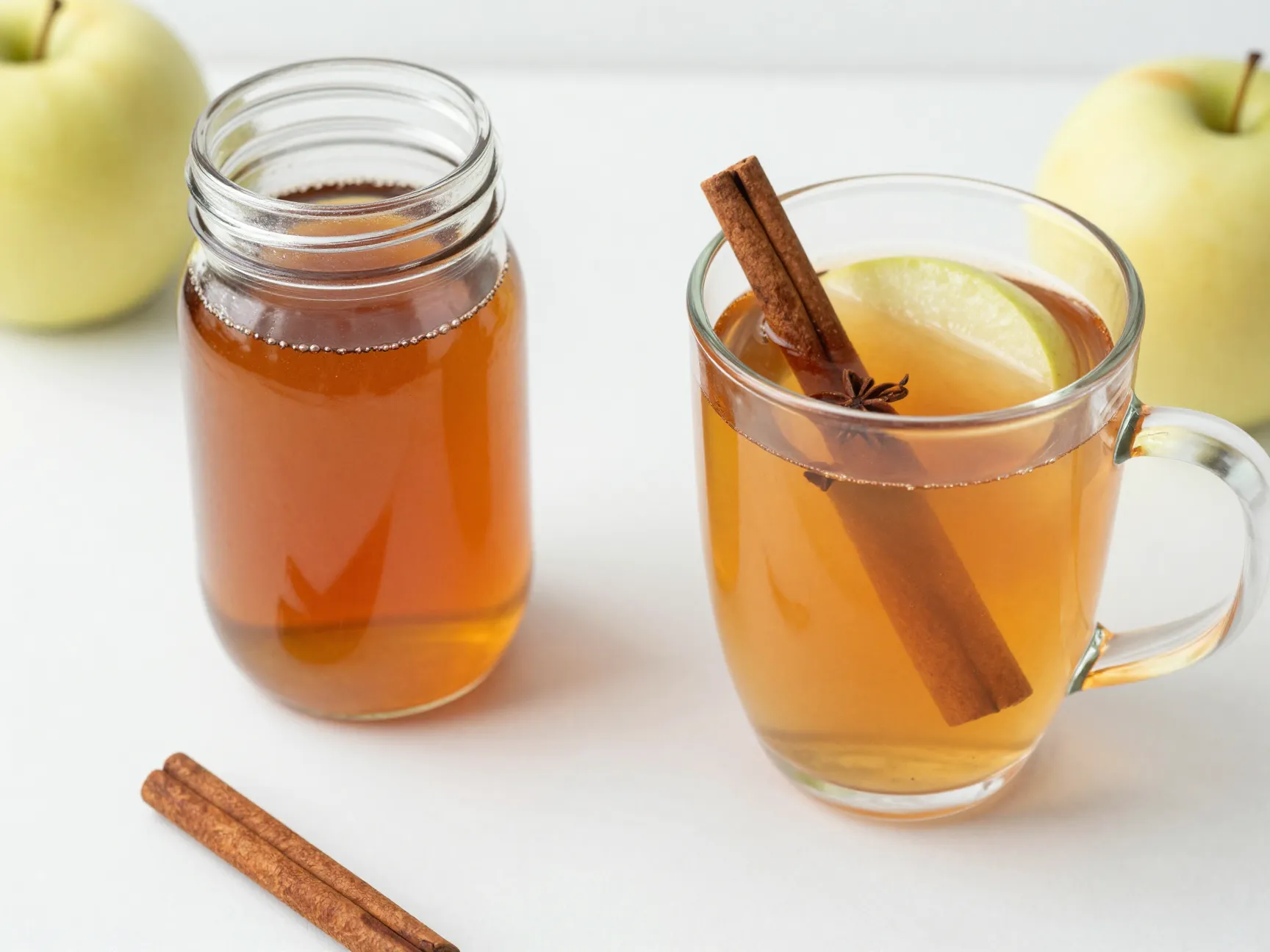 Spiced apple syrup concentrate in jar beside hot infused drink