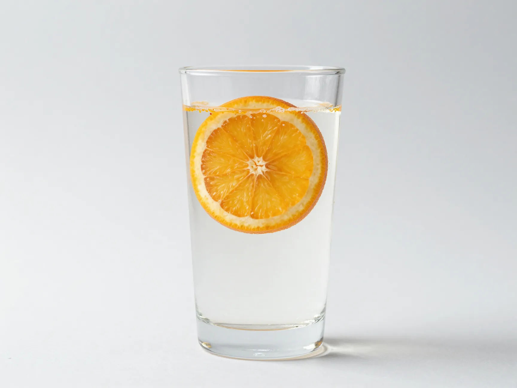 Minimalist citrus wheel sparkling water clear glass white background