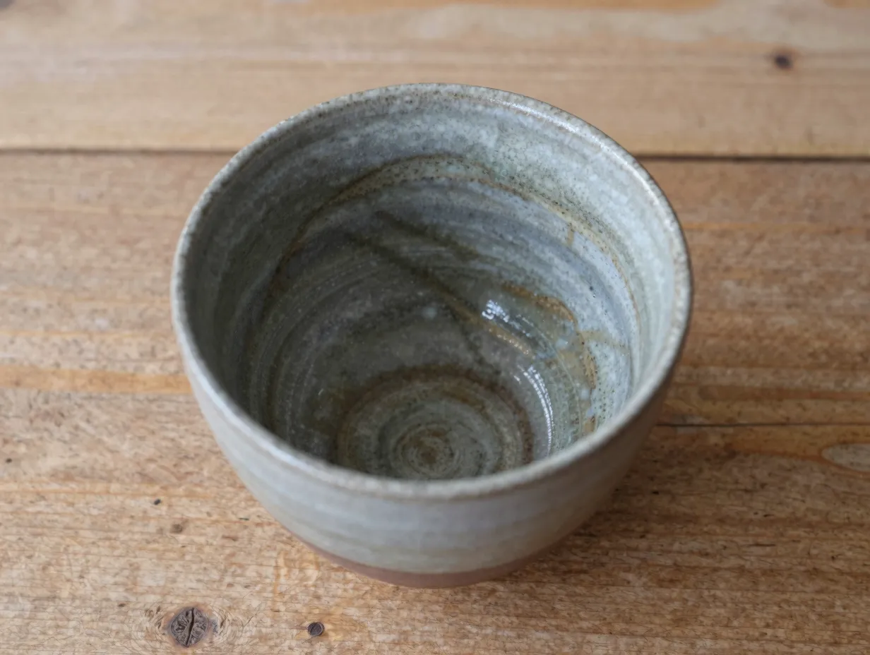 Ash glazed stoneware wine cup streaked surface wood
