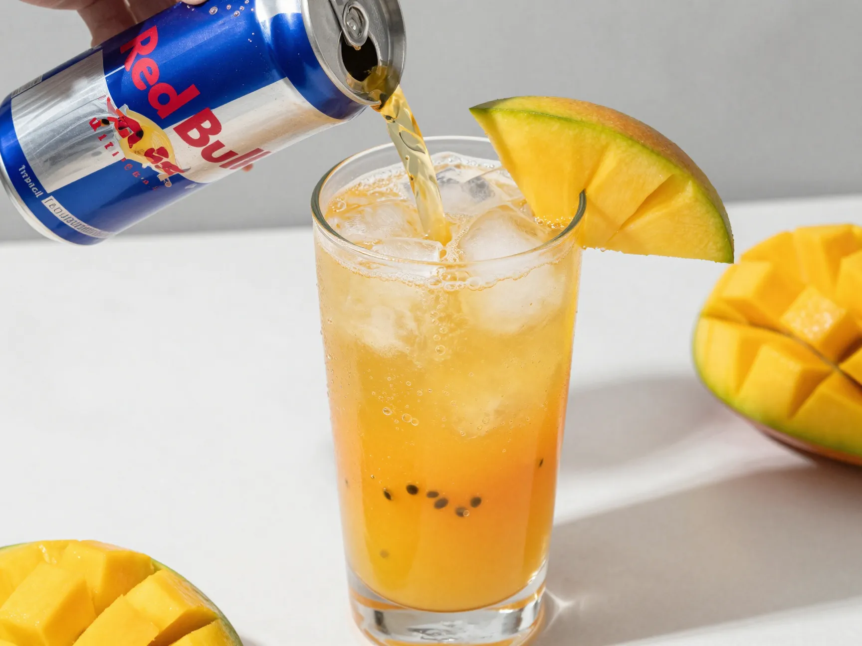 Tropical mango passion fruit red bull drink in tall glass with ice