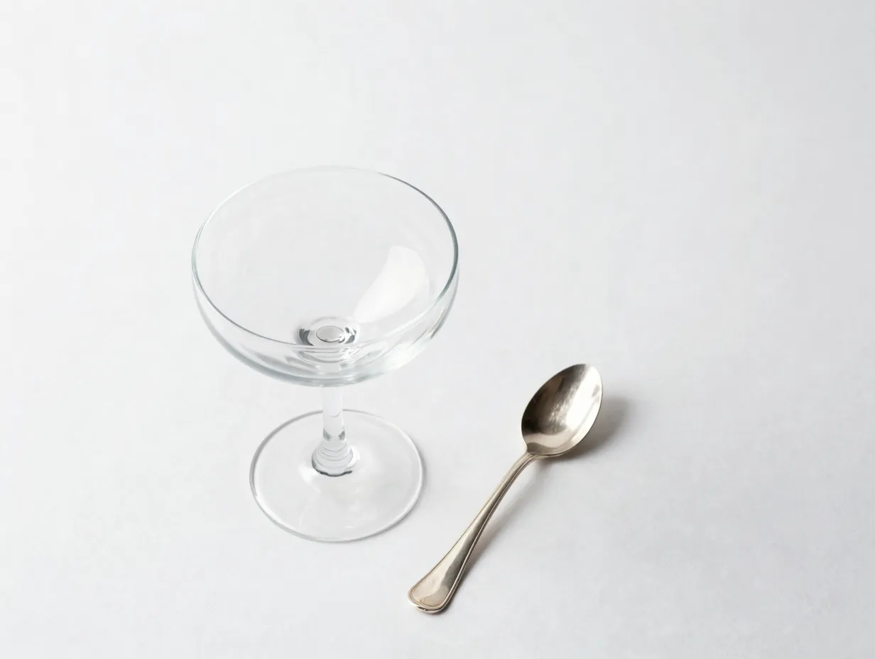 Elegant coupe glass sidecar cocktail on white minimalist background with vintage spoon