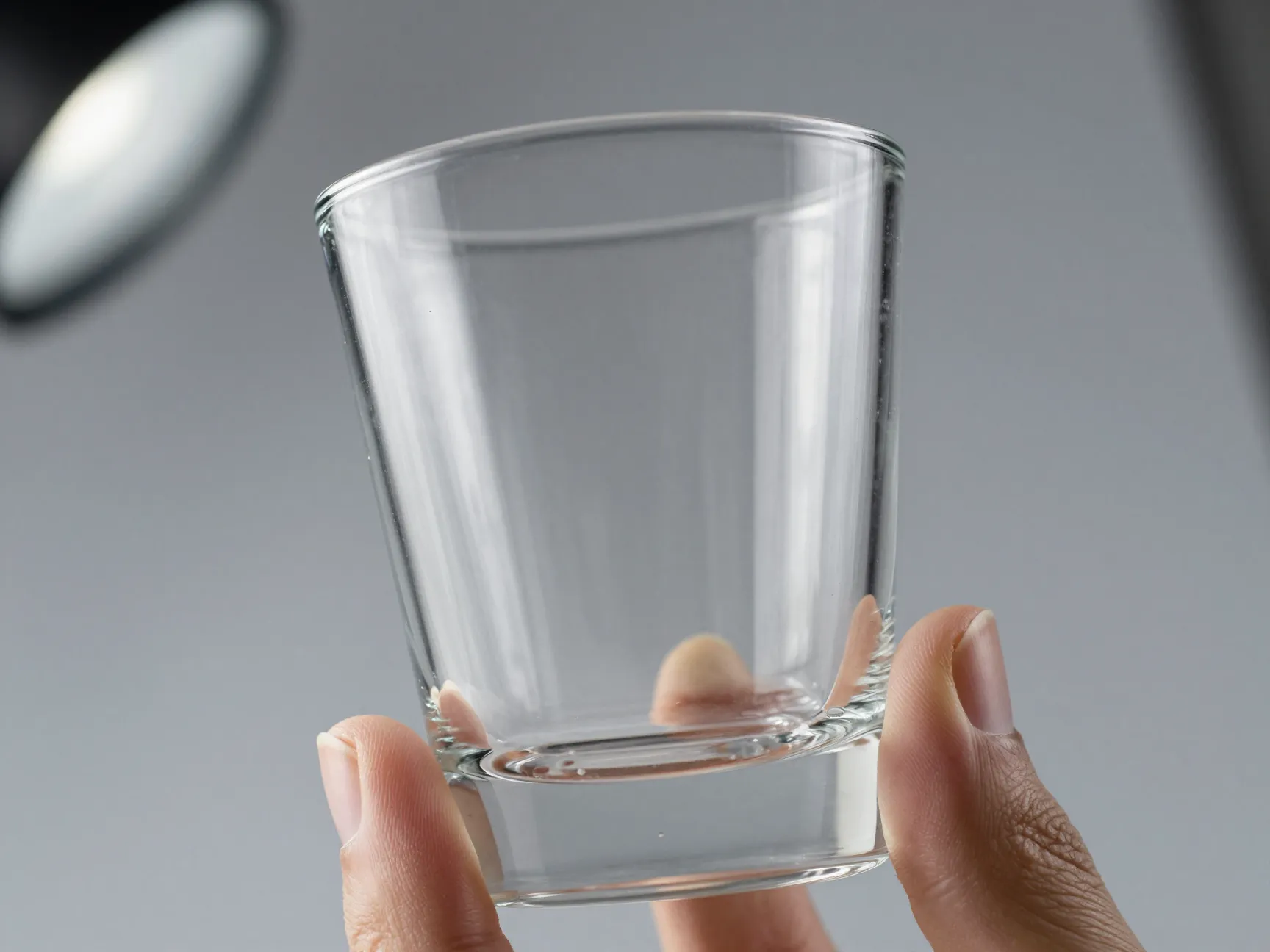 Crystal clear clean highball glass under studio light inspection for smudges